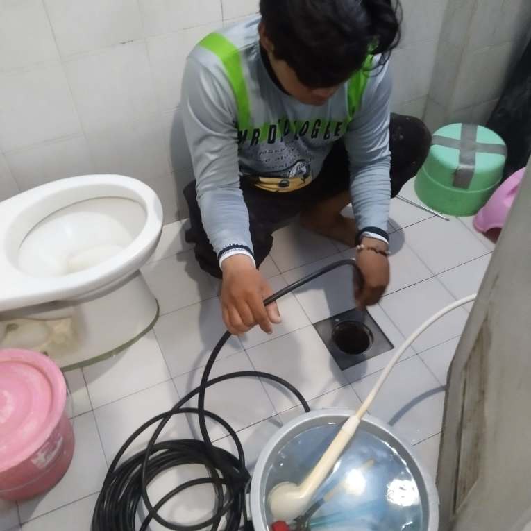 Mr. Declogger technician unclogging a bathroom floor drain in Cebu
