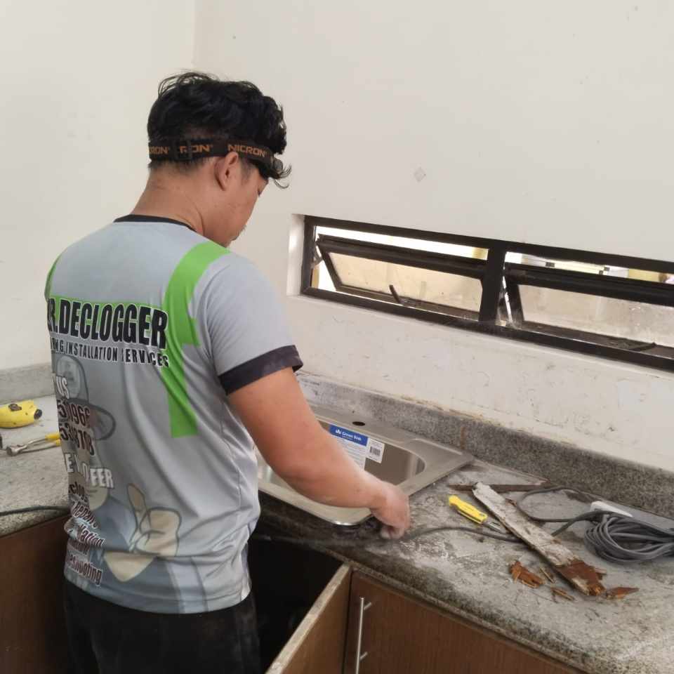 Plumber installing a stainless kitchen sink in a Cebu home